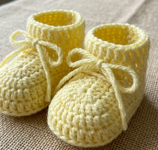 Par de sapatinhos de bebê em amarelo claro